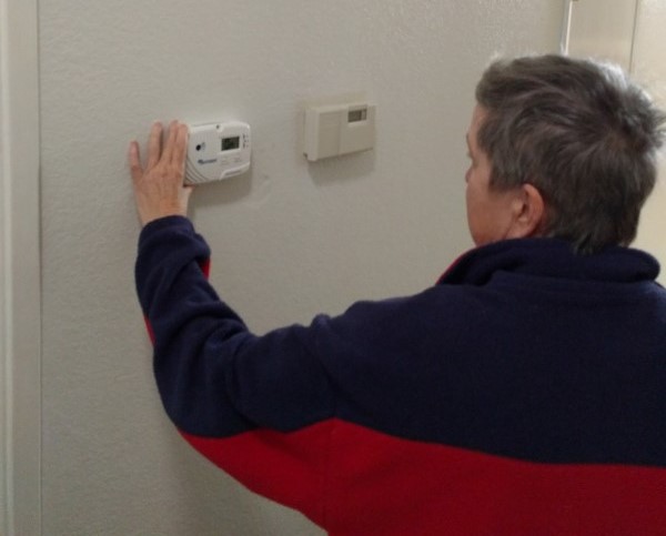 "Donna inspecting new thermostat installed by LIHEAP."